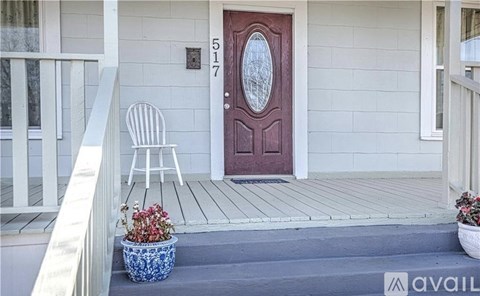 A red door with a white frame is on a house with a blue planter on the steps.