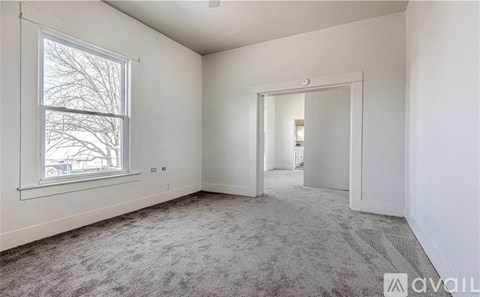 A room with a carpeted floor and a window with a view of trees outside.