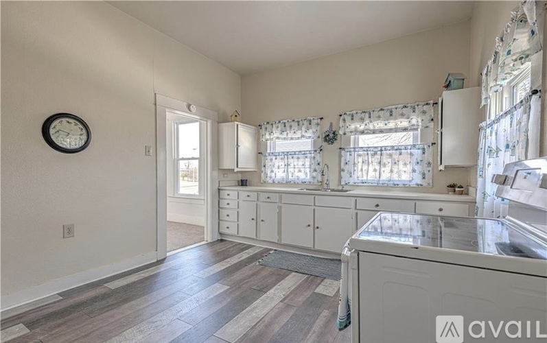 A kitchen with a white cabinet and a clock on the wall.