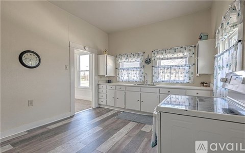 A kitchen with a white cabinet and a clock on the wall.