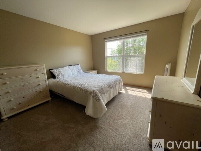 A bedroom with a bed, dresser, and window.