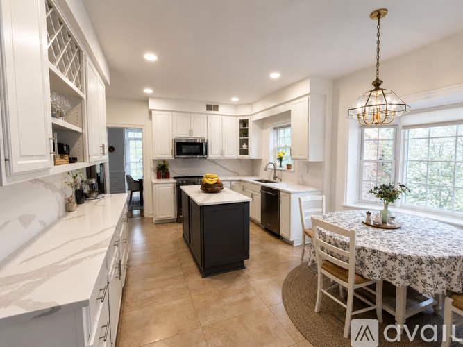 A kitchen with white cabinets and a black island.