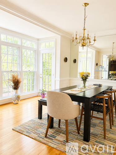A dining room with a table set for two and a chandelier hanging from the ceiling.