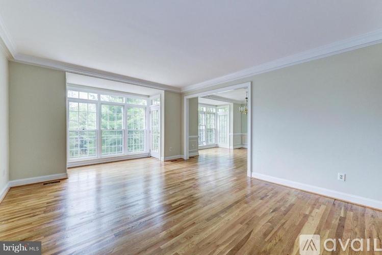 A spacious room with wooden floors and large windows.