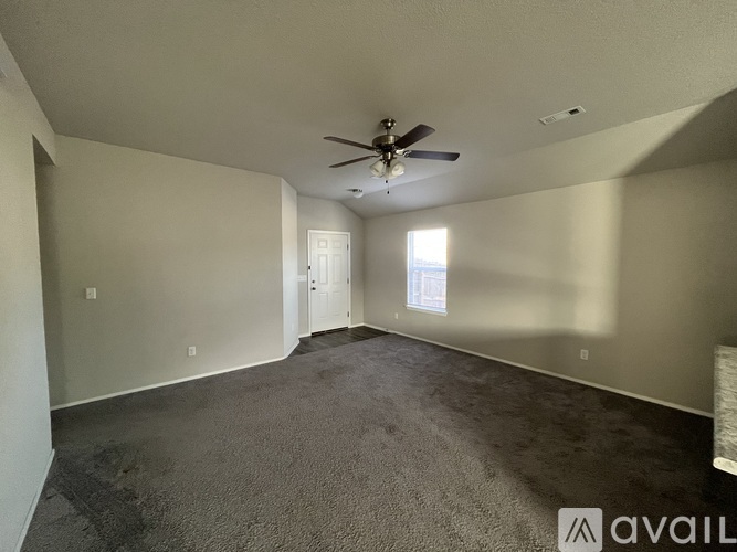 A spacious room with a ceiling fan and carpeted floor.