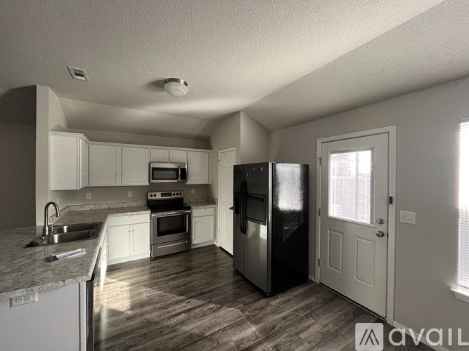 A kitchen with white cabinets and a black refrigerator.