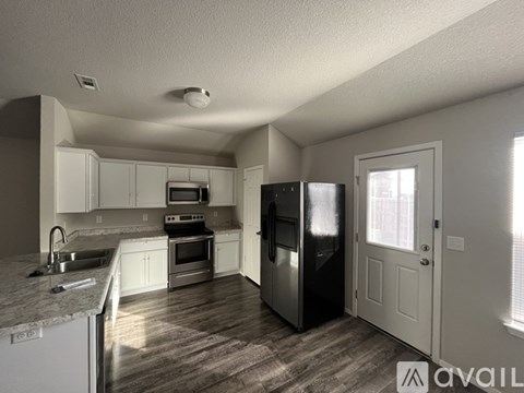 A kitchen with white cabinets and a black refrigerator.