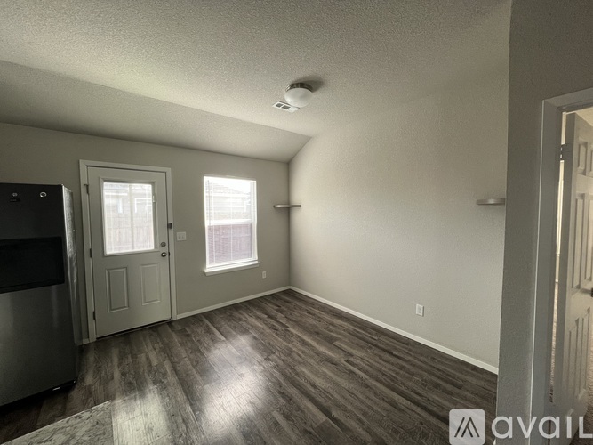 A room with a wooden floor and a window with blinds.