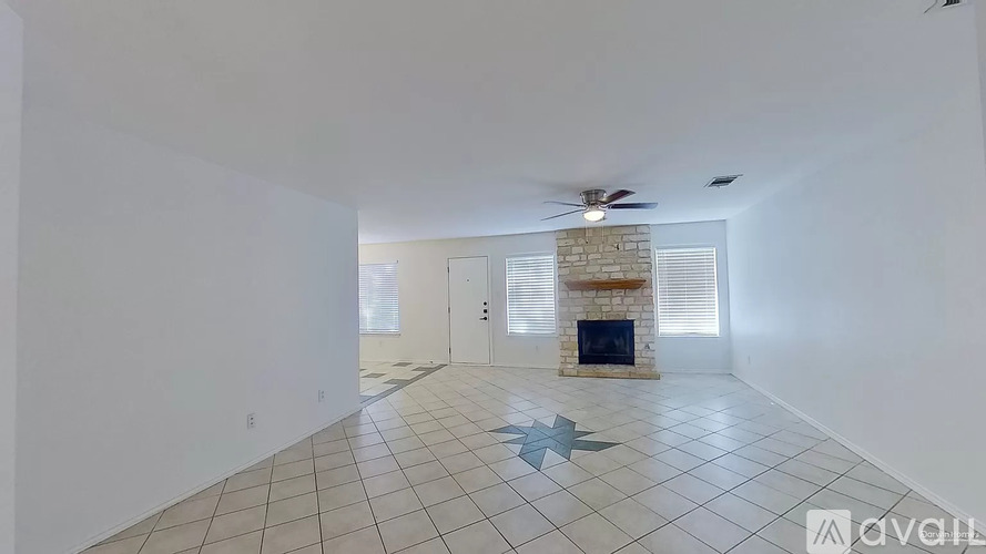 A spacious room with a fireplace and a ceiling fan.
