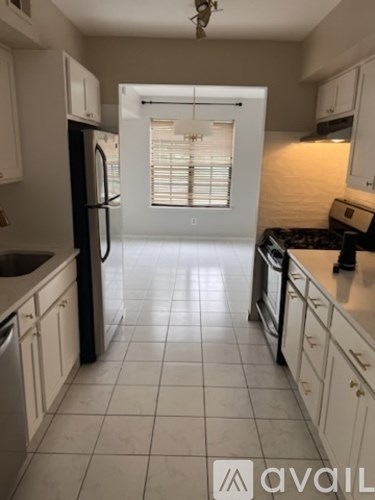 A kitchen with white cabinets and a black fridge.