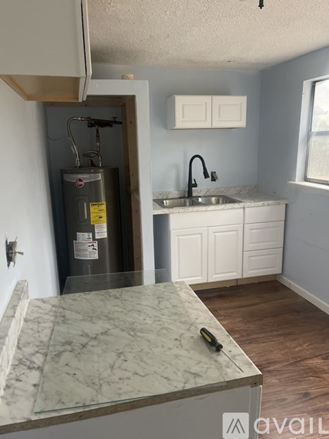 A kitchen with a marble countertop and a water heater installed in the wall.