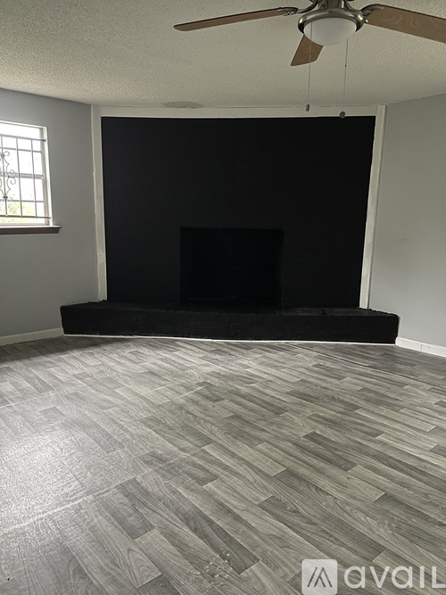 A living room with a fireplace and a fan.