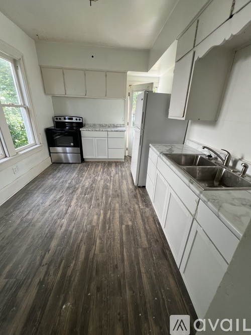 A kitchen with wooden floors and white cabinets.
