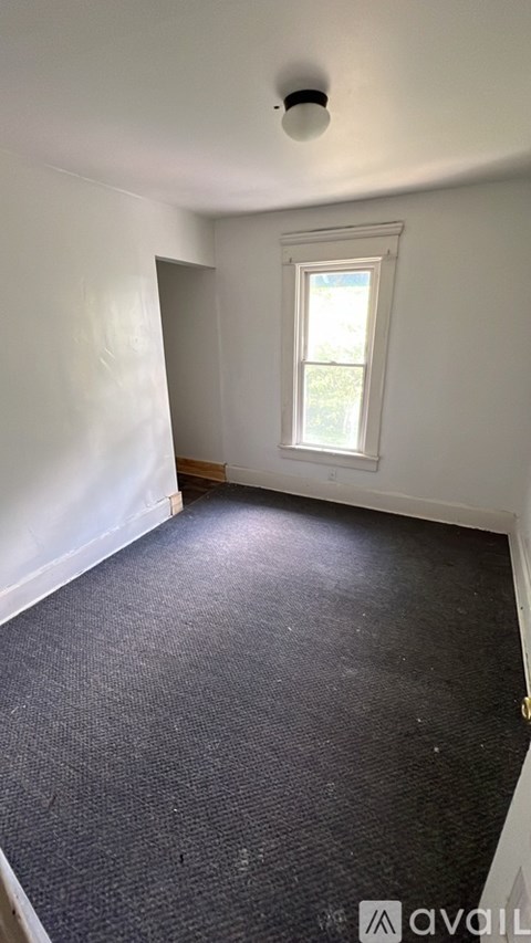 A room with a window and a carpeted floor.