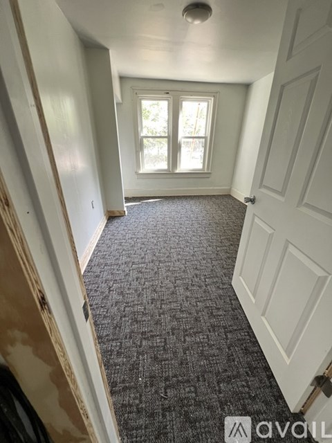 A hallway with a carpeted floor and a door on the right.