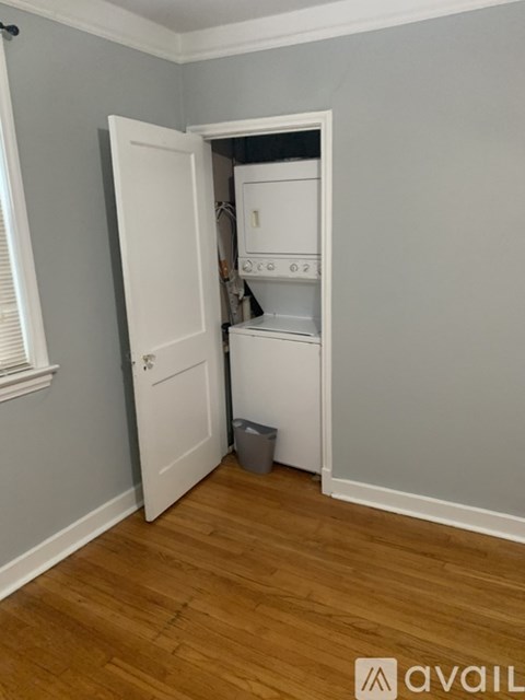 A small white fridge in a room with wooden floors and grey walls.