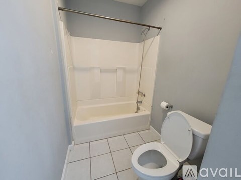 A white toilet is in a small bathroom with a walk-in shower.