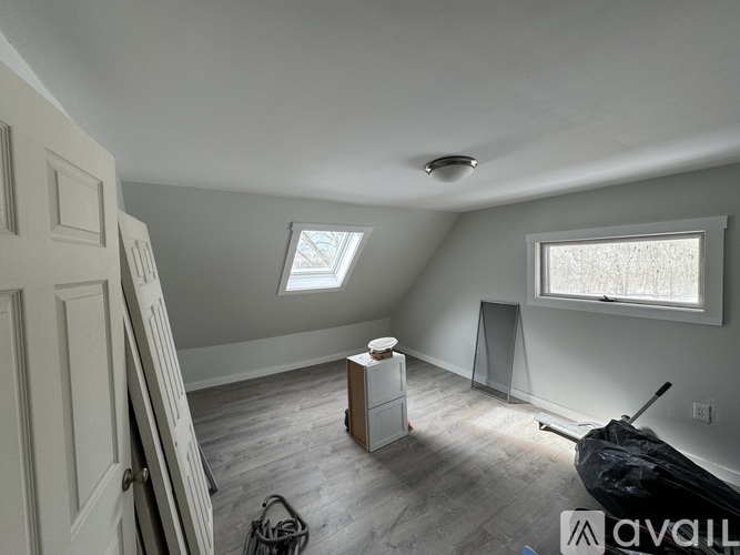 A room with a window, a wooden cabinet, and a black bag on the floor.