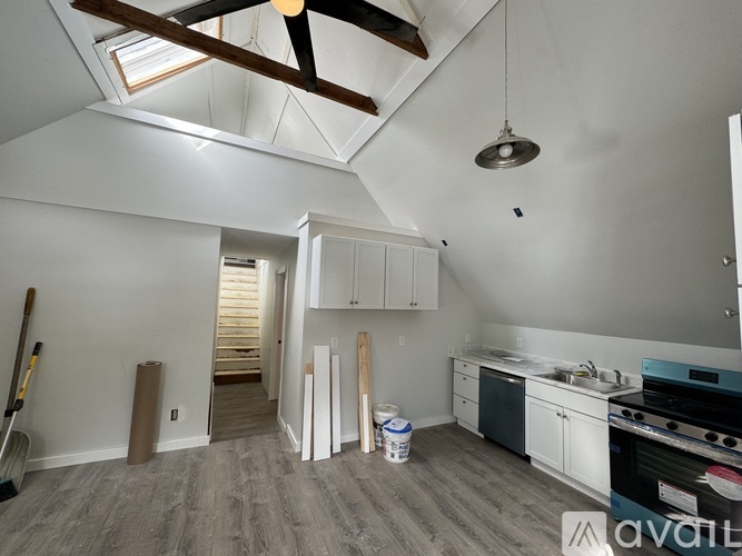 A room with a ceiling fan and a kitchen area with a stove and cabinets.