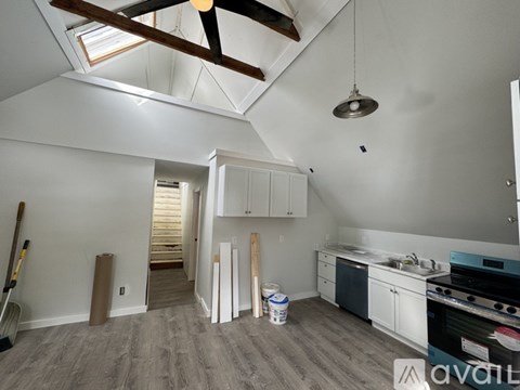 A room with a ceiling fan and a kitchen area with a stove and cabinets.
