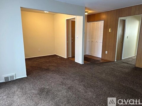 A room with a carpeted floor and three doors.
