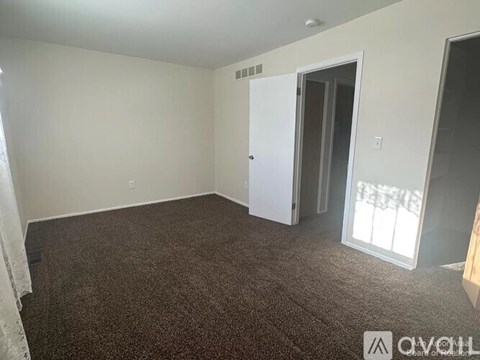 A room with a carpeted floor and a door leading to another room.