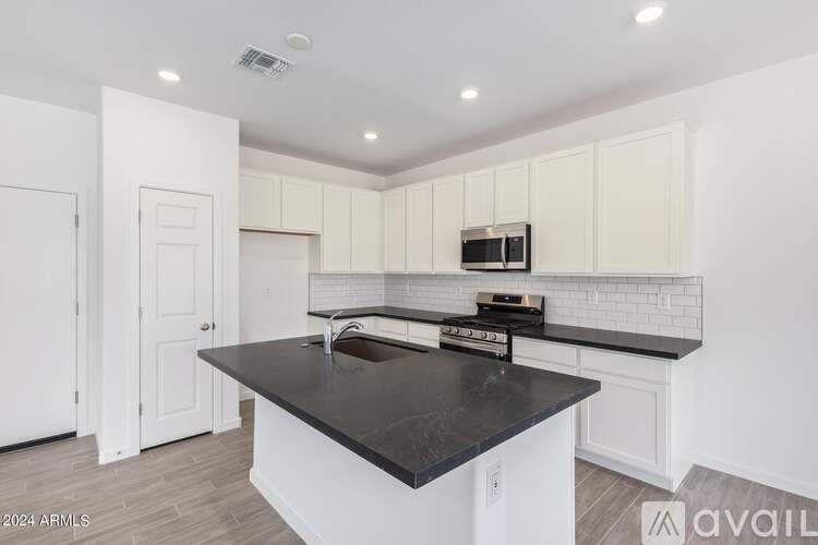 A kitchen with white cabinets and a black countertop.