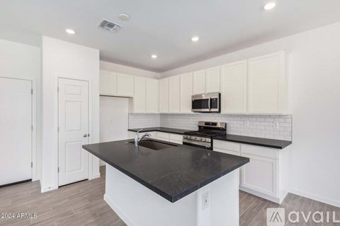 A kitchen with white cabinets and a black countertop.