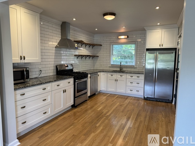 A kitchen with wooden floors and white cabinets.