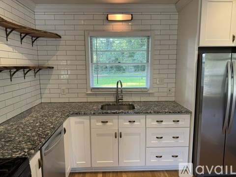 A kitchen with white cabinets and a black granite countertop.