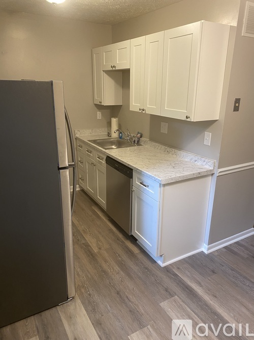 A kitchen with white cabinets and a black refrigerator.