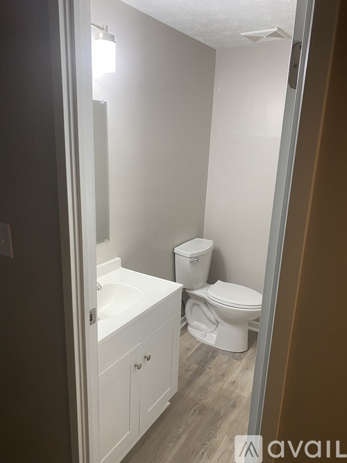 A bathroom with a toilet, sink, and cabinet.