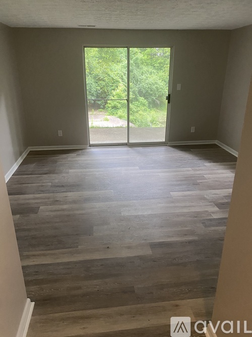 A room with wooden flooring and a sliding glass door leading outside.