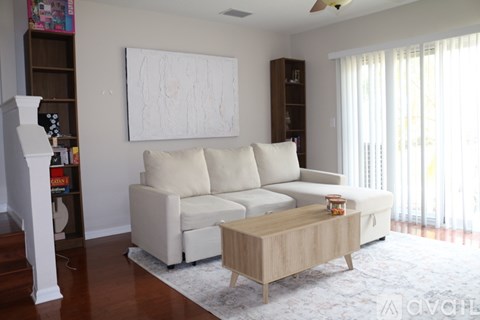 A living room with a white couch and a wooden coffee table.