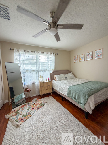 A bedroom with a bed, dresser, mirror, and a ceiling fan.