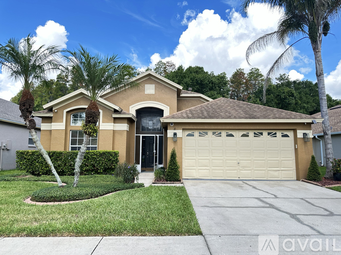 A house with a garage and palm trees in front.