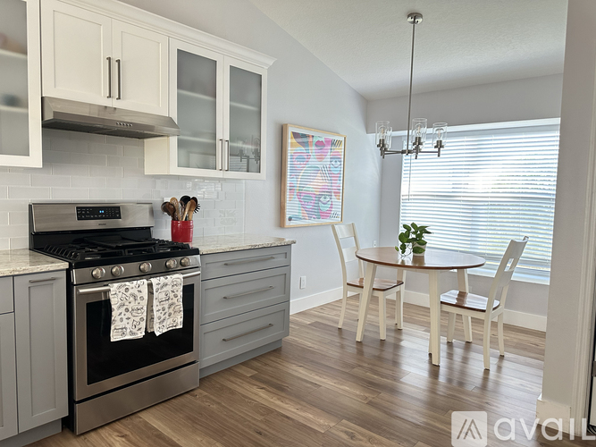 A kitchen with a stove, oven, and a dining table with chairs.