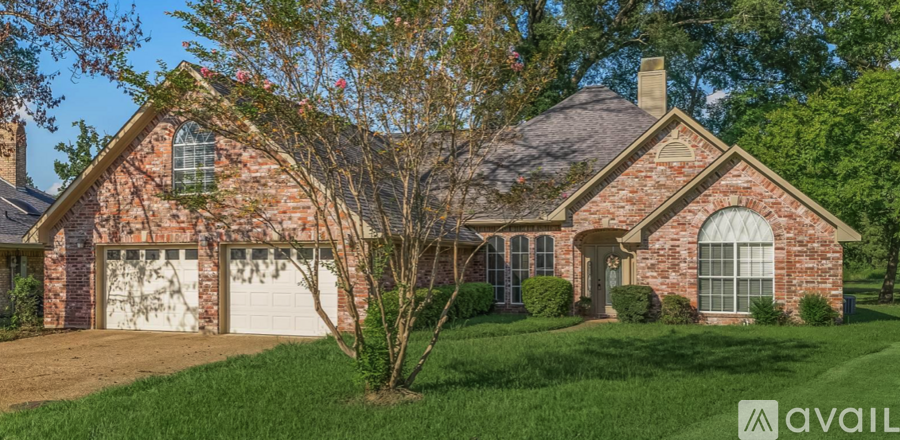 A brick house with a white garage door and a tree in front.