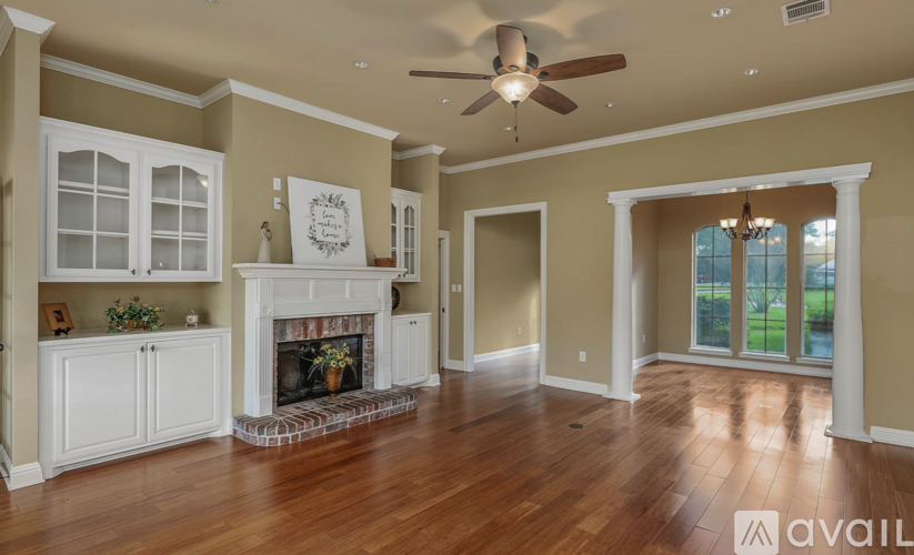 A spacious living room with a fireplace and a ceiling fan.