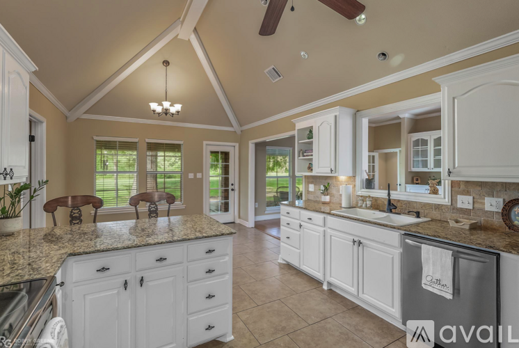 A kitchen with white cabinets and a marble countertop.
