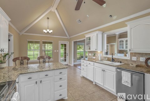 A kitchen with white cabinets and a marble countertop.