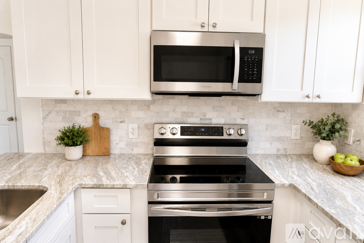 A kitchen with a stainless steel oven and microwave above a marble countertop.