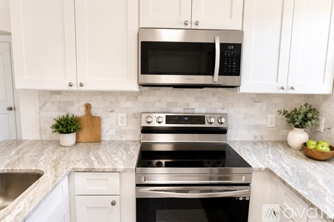 A kitchen with a stainless steel oven and microwave above a marble countertop.