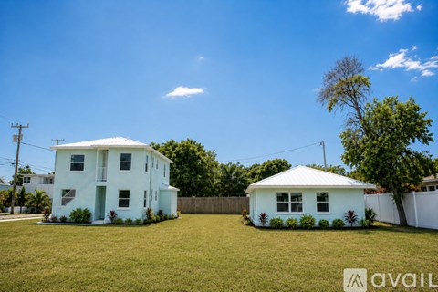 Two houses with white exteriors are situated in a grassy area.