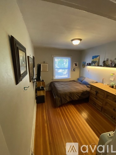 A bedroom with a bed, dresser, and a window.