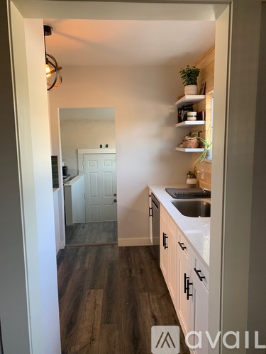 A kitchen with white cabinets and a wooden floor.