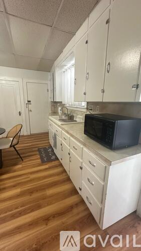 A kitchen with white cabinets and a black microwave.