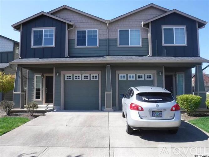 A grey car is parked in front of a grey and blue house.