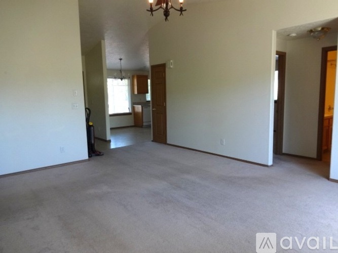A spacious living room with a chandelier and a door on the right.