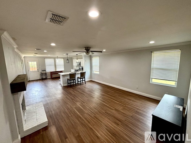 A living room with a wooden floor and a dining area with a table and chairs.